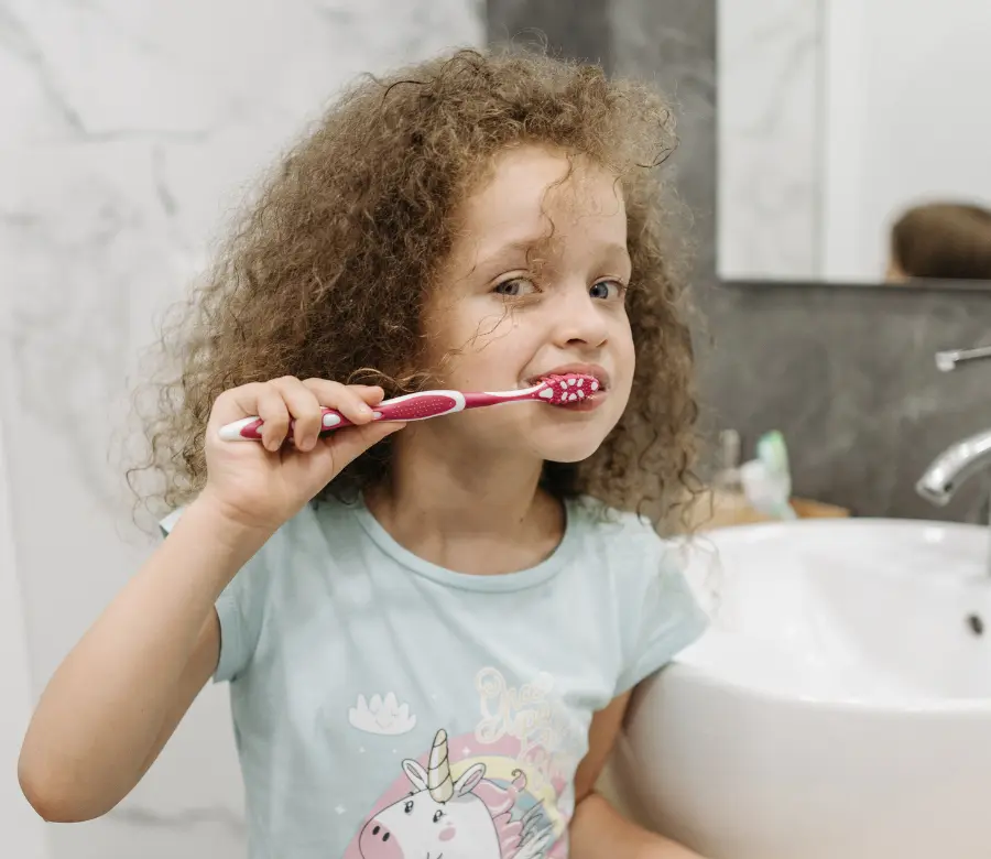 A young girl brushing her teeth at the bathroom sink